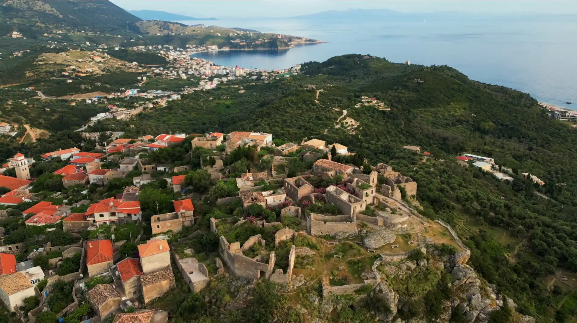 Panorama Himare w Albanii z ruinami starego miasta, zielonymi wzgórzami i wybrzeżem Morza Jońskiego