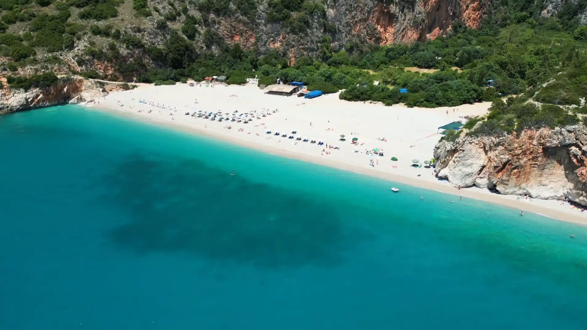 Plaża Gjipe w Albanii z turkusową wodą, jasnym piaskiem i klifami otaczającymi zatokę