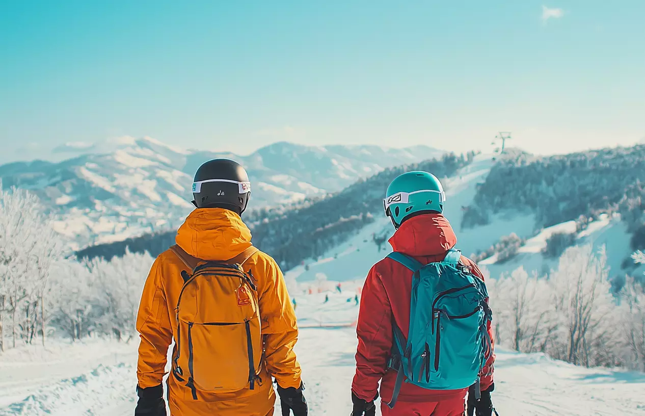 Para narciarzy patrząca w dół stoku i na odległe góry.